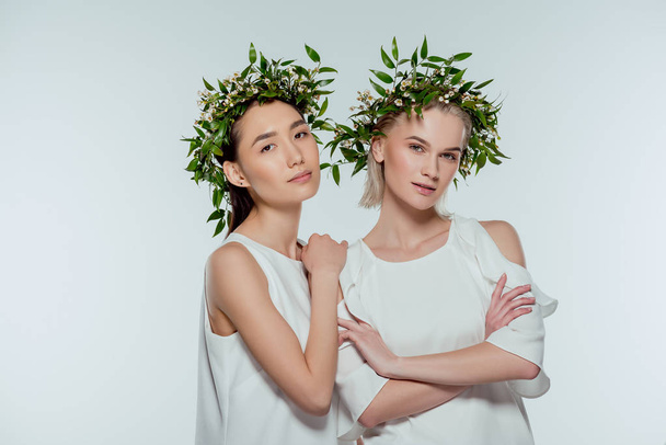 chicas multiétnicas atractivas posando en vestidos blancos y coronas florales, aisladas en gris, belleza natural
 - Foto, imagen