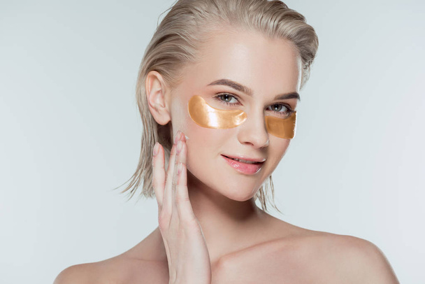 attractive girl with golden eye patches, isolated on grey - Foto, Imagen