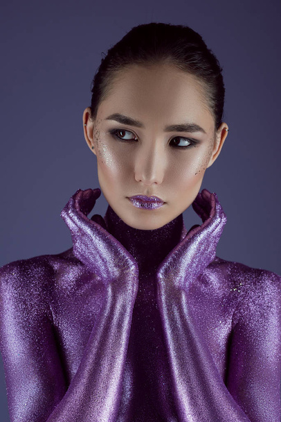 стильная привлекательная азиатская девушка в ультрафиолетовом блеске, изолированная на фиолетовый
 - Фото, изображение