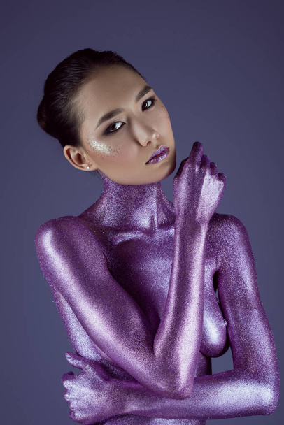 fashionable nude asian girl in ultra violet glitter, isolated on purple - Photo, image