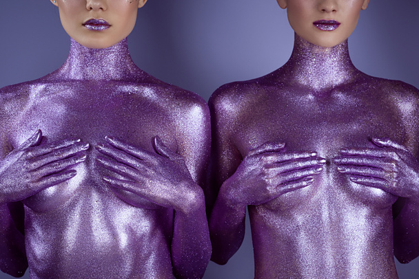 cropped view of nude girls in ultra violet glitter covering breasts, isolated on purple - Zdjęcie, obraz