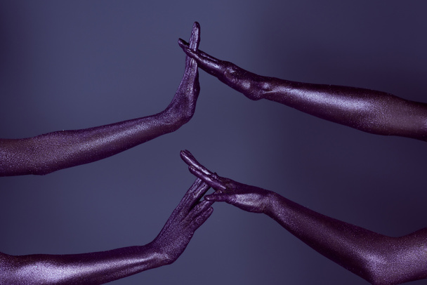partial view of female hands in purple glitter touching each other, isolated on violet - Foto, Imagen