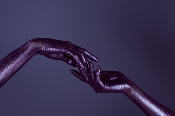 partial view of womens hands in ultra violet glitter touching each other, isolated on purple - Фото, зображення