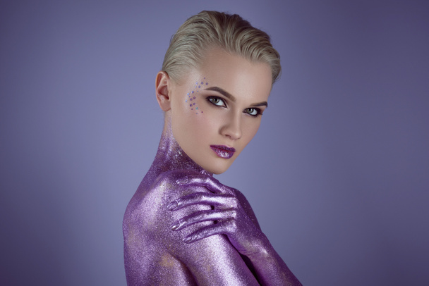 fashionable girl posing in purple glitter, isolated on violet - Foto, imagen