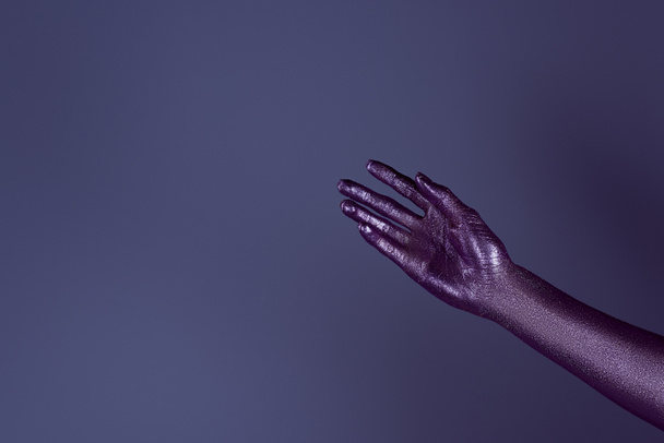 gedeeltelijke weergave van tedere hand in ultra violet glitter, geïsoleerd op paars - Foto, afbeelding