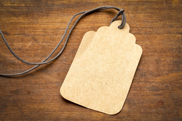 τιμή tag λευκό χαρτί με ένα μακρύ σπάγκο εναντίον κοκκιώδες ξύλο ρουστίκ - Φωτογραφία, εικόνα