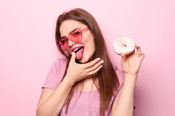Attractive girl posing with doughnut on color background - Фото, изображение