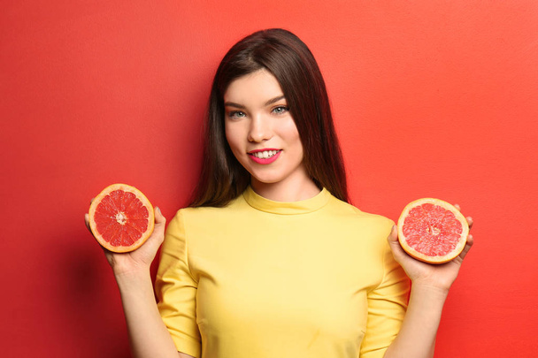 Beautiful young woman with halves of grapefruit on color background - Foto, Imagen