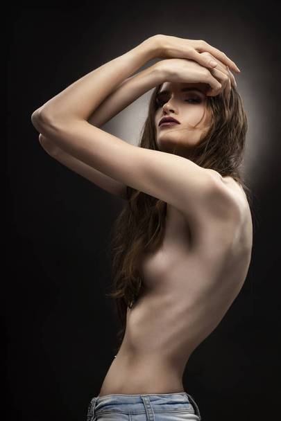 Beautiful slim flexible athletic topless girl model covers her naked breast with her hair on grey black gradient background. Healthy skin. Copy space. Advertising, commercial and conceptual design. - Φωτογραφία, εικόνα