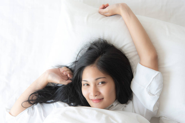 Hermosa mujer asiática que duerme en la cama cómodamente y alegremente. , Mujer estilo de vida en el hogar que descansa en la cama en dormitorio. - Foto, imagen