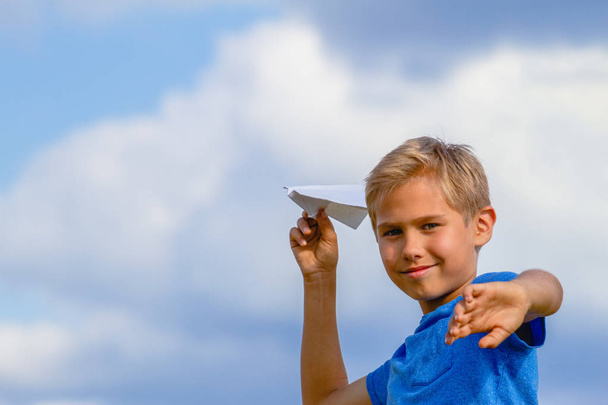 Boy throwing paper plane on summer day - Фото, изображение