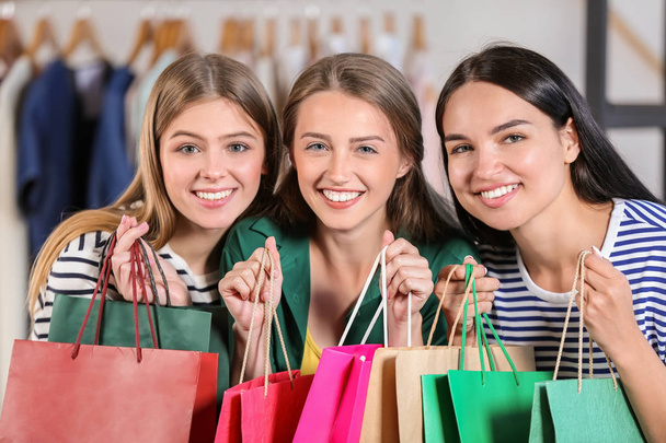 Young beautiful girls with shopping bags in clothing shop - Photo, Image
