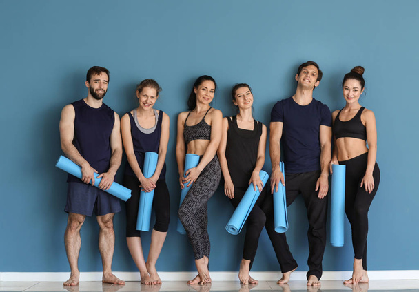 Grupo de personas con esteras de yoga cerca de la pared de color
 - Foto, Imagen