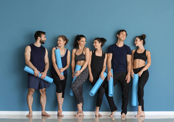 Group of people with yoga mats near color wall - Foto, Imagen