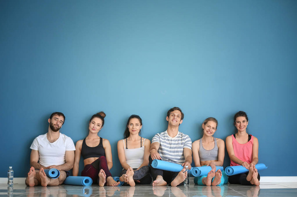 Grup ile yoga paspaslar renk duvarının yakınında katta oturan insan - Fotoğraf, Görsel