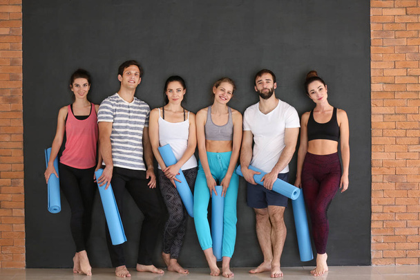 Gruppe von Menschen mit Yogamatten auf dunklem Hintergrund - Foto, Bild