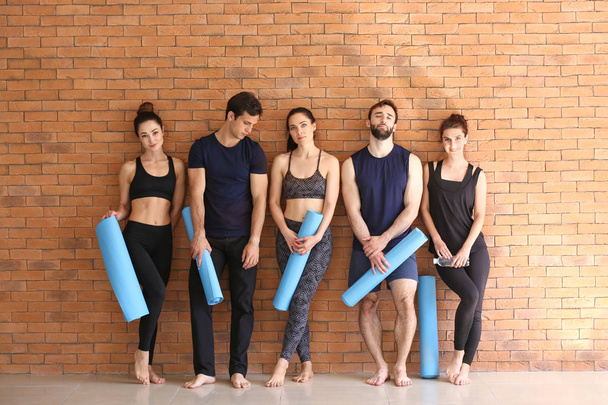 Birlikte yoga paspaslar tuğla duvar yakınındaki grup insan - Fotoğraf, Görsel