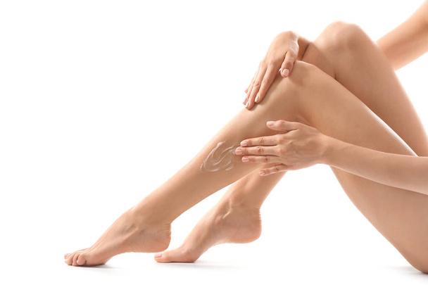 Nuori nainen soveltamalla kerma hänen jalka jälkeen depilation valkoisella pohjalla
 - Valokuva, kuva