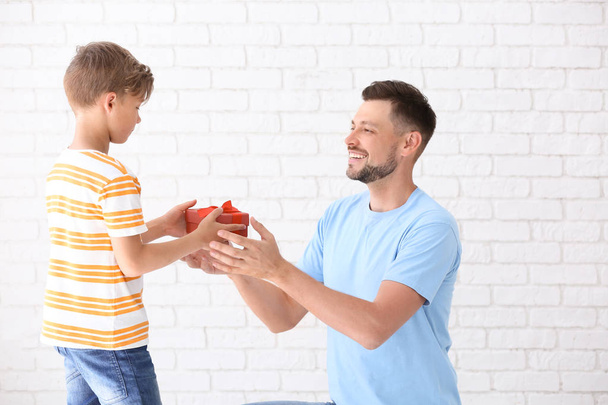 Man receiving gift for Father's Day from his son on light background - Photo, Image