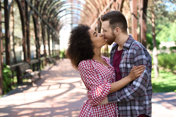 junge liebende interrassische Paare küssen sich im Park an einem Frühlingstag - Foto, Bild