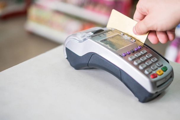 Рука перериває кредитну картку на платіжному терміналі в супермаркеті
 - Фото, зображення