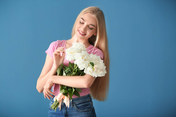 Ελκυστική νεαρή γυναίκα με όμορφα λουλούδια στο χρώμα φόντου - Φωτογραφία, εικόνα