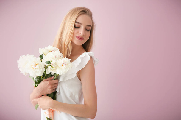 Atraktivní mladá žena s krásnými květinami na barvu pozadí - Fotografie, Obrázek