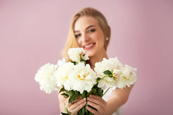 Attractive young woman with beautiful flowers on color background - Photo, Image