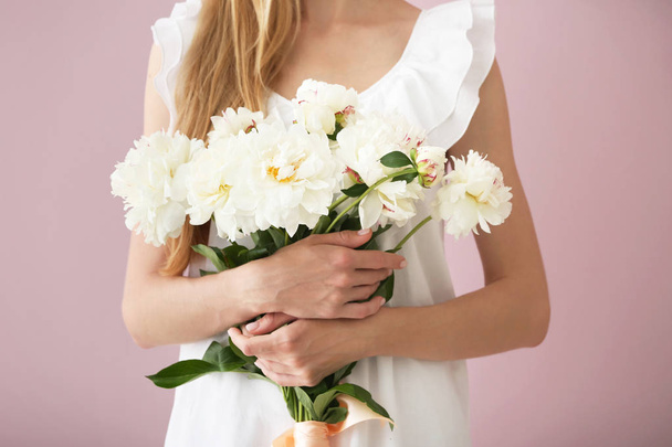 Ελκυστική νεαρή γυναίκα με όμορφα λουλούδια στο χρώμα φόντου - Φωτογραφία, εικόνα