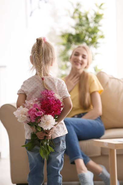 Χαριτωμένο μικρό κορίτσι κρύβεται μπουκέτο λουλούδια για την μητέρα του πίσω από την πλάτη - Φωτογραφία, εικόνα