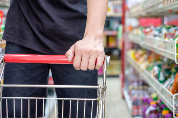 Cliente con carrito de compras eligiendo el producto en el supermercado
 - Foto, Imagen