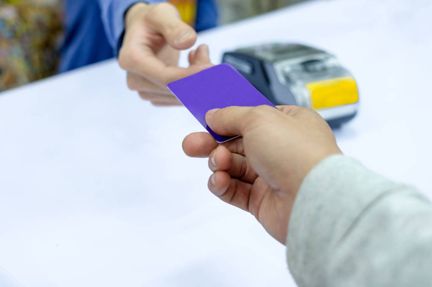 Cartão de crédito pago à mão no terminal de pagamento com caixa do pessoal
 - Foto, Imagem