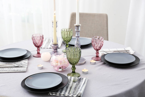 Burning candles with dishware and cutlery on table in dining room - Fotoğraf, Görsel