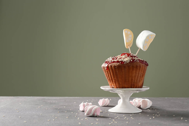 Suporte de sobremesa com delicioso cupcake na mesa contra fundo de cor
 - Foto, Imagem