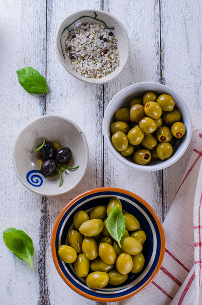 Sortiment von Oliven mit Kräutern und Meersalz auf weißem Holzrücken - Foto, Bild