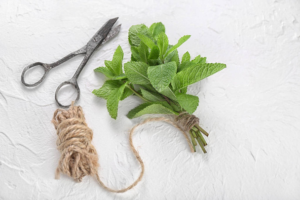 Fresh mint, scissors and thread on light background - Photo, image