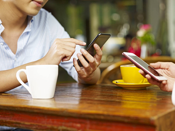 mains de l'homme et de la femme utilisant des téléphones mobiles dans un café
. - Photo, image
