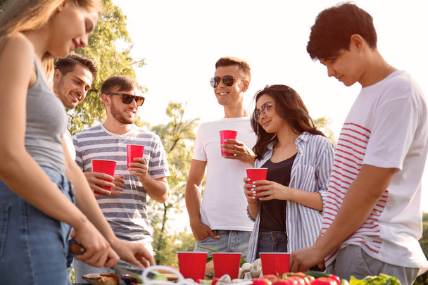Νέοι άνθρωποι έχοντας μπάρμπεκιου πάρτι στην ηλιόλουστη ημέρα σε εξωτερικούς χώρους - Φωτογραφία, εικόνα