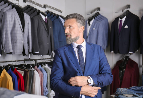 Красивый зрелый мужчина в стильном костюме в магазине мужской одежды
 - Фото, изображение
