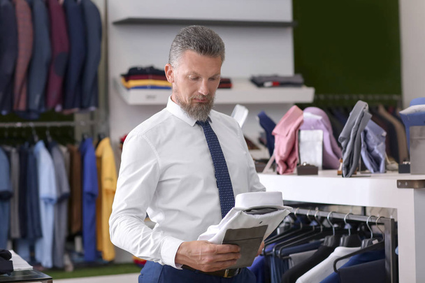 Przystojny mężczyzna dojrzały, wybierając ubrania w sklepie - Zdjęcie, obraz