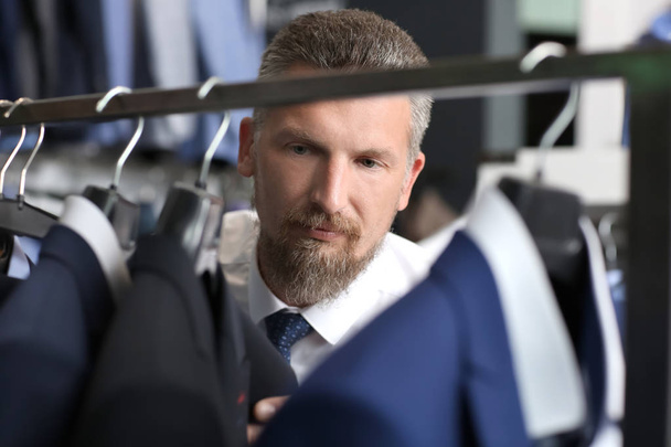 Handsome mature man choosing clothes at store - Photo, Image
