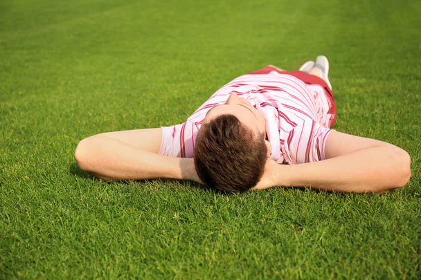 Jeune homme relaxant sur l'herbe verte à l'extérieur
 - Photo, image