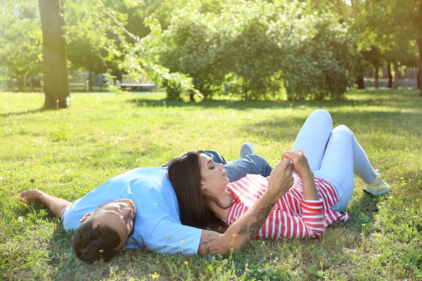 Happy couple lying on grass in park - Zdjęcie, obraz