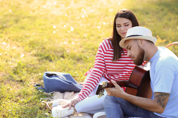 Happy couple with guitar in park on spring day - Foto, Bild