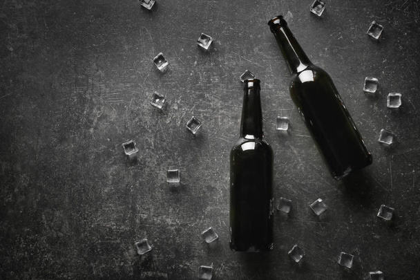 Μπουκάλια μπύρας με παγάκια σε σκούρο φόντο - Φωτογραφία, εικόνα