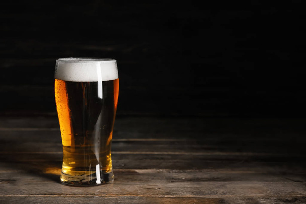 Bicchieri con birra fredda su tavolo di legno su sfondo scuro
 - Foto, immagini