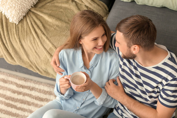 Щаслива молода пара п'є гарячу каву під час відпочинку вдома
 - Фото, зображення