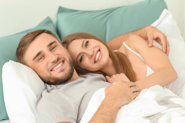 Happy νεαρό ζευγάρι ανάπαυση στο κρεβάτι στο σπίτι - Φωτογραφία, εικόνα