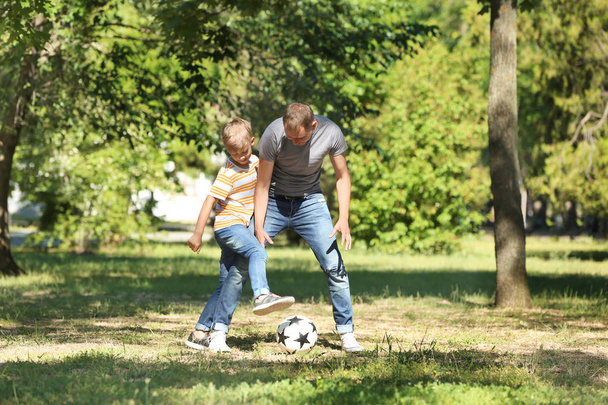 Happy father and son playing football in park - Foto, imagen