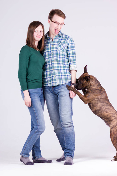 Beautiful young couple with dog on white background - Foto, immagini